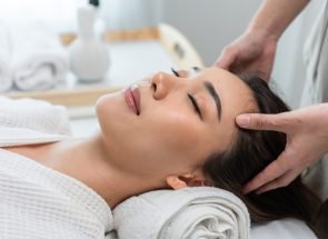 Asian young woman feel happy and relax during facial and head massage. Attractive beautiful girl lying on massage table, getting physiotherapy from masseuse for skin and body care in spa beauty salon.