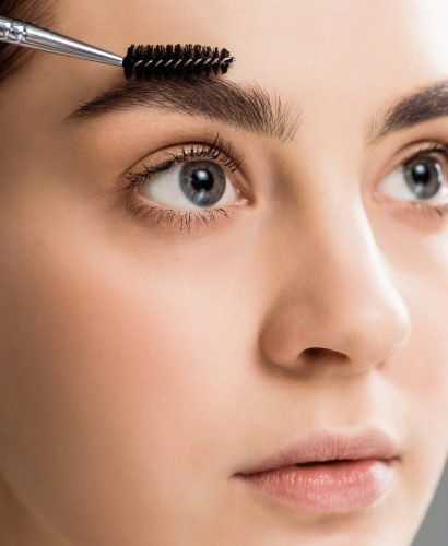 beautiful young woman styling eyebrow with eyebrow brush