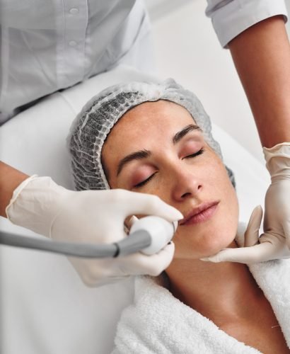 A woman is receiving a facial treatment while relaxed on a treatment bed.