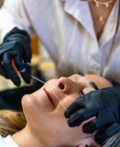 Professional eyebrow beautician. Facial hair removal with thread.