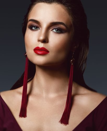 Portrait of stunning woman with a beautiful makeup wearing long red earrings